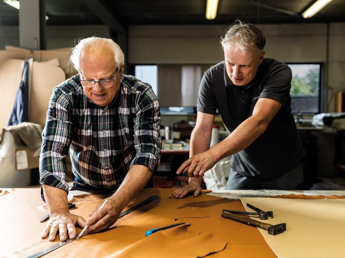 Upholstery instructor guiding a student while marking a pattern on leather