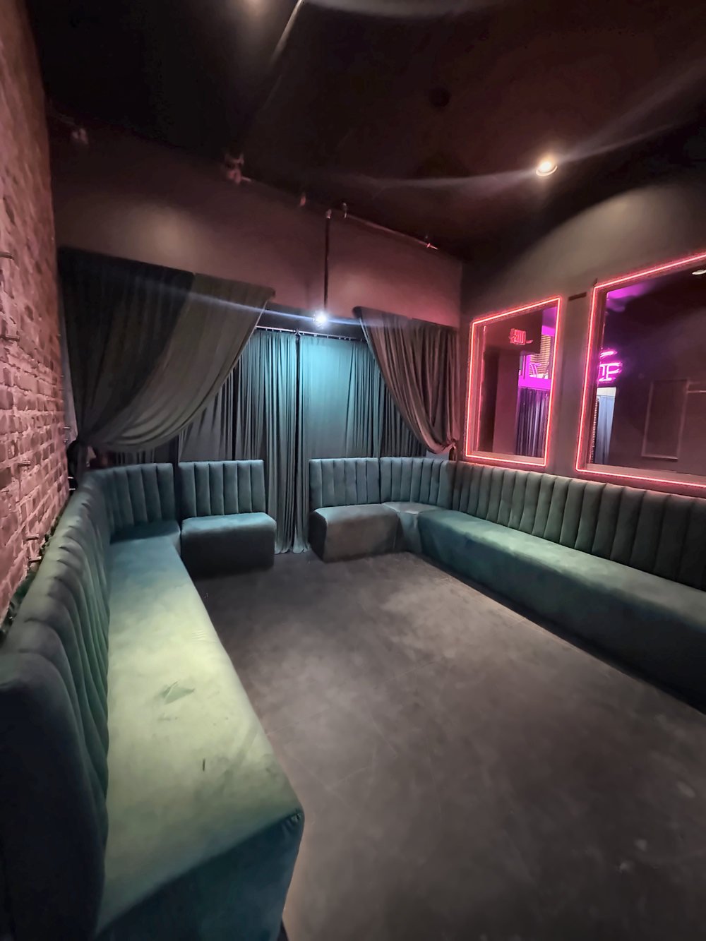 Green velvet banquette corner lounge with red neon light accents