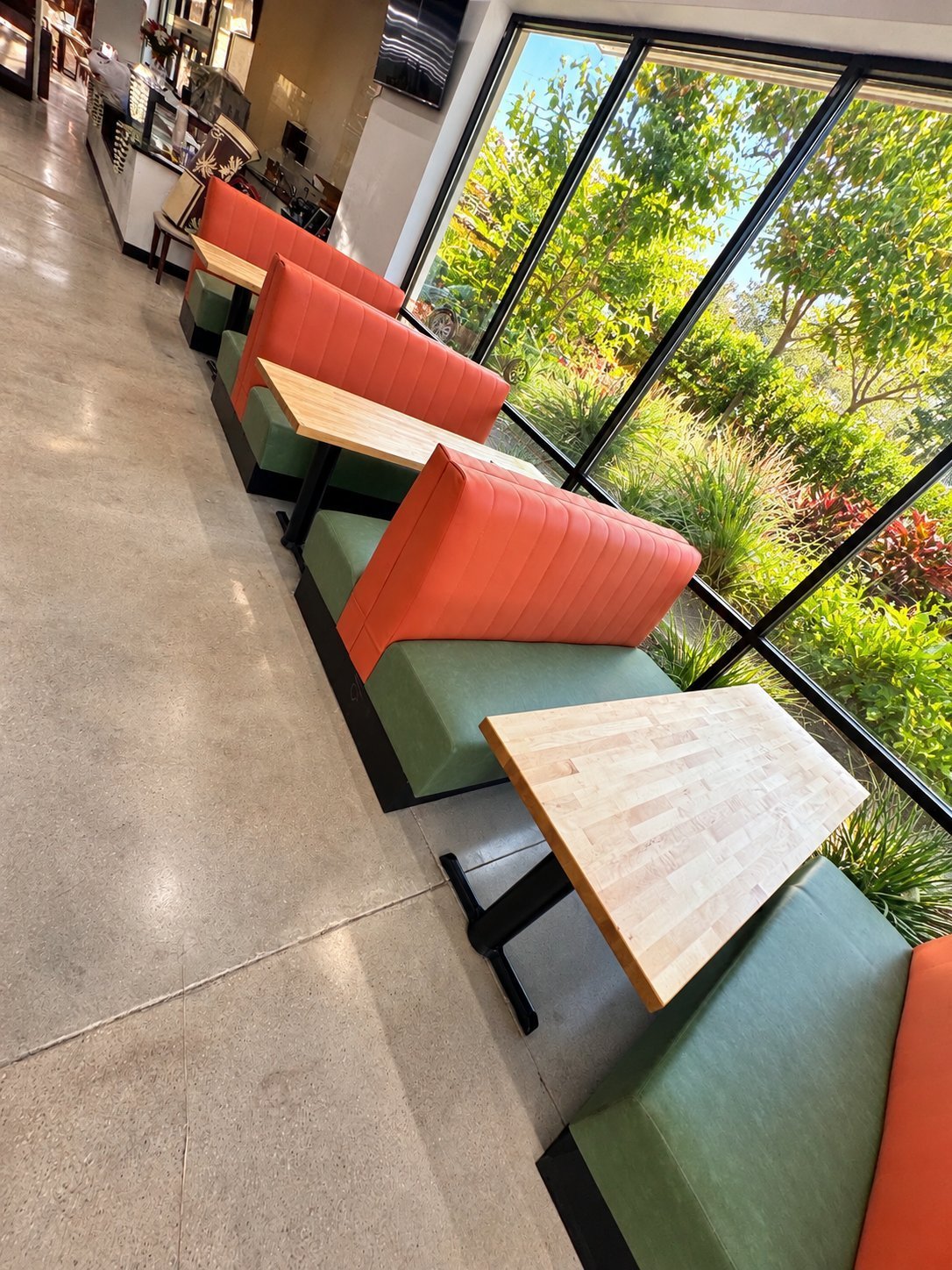Row of orange and green leather restaurant booths with channel stitching and light wood tables