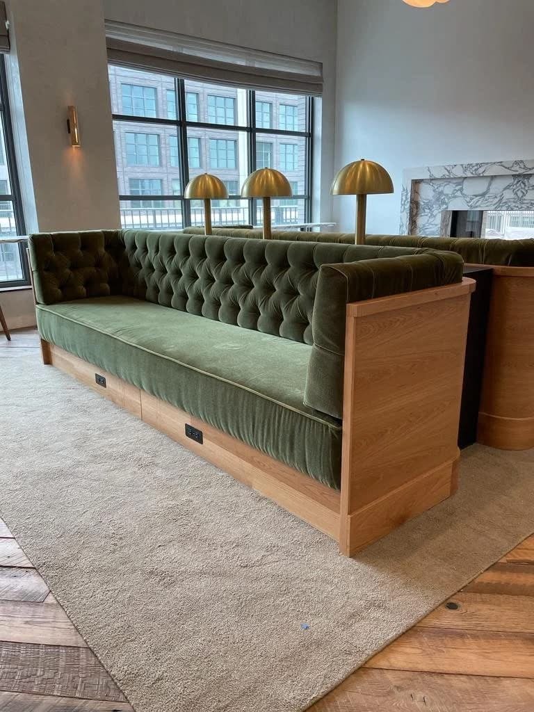 Green tufted velvet restaurant sofa with oak frame and brass table lamps