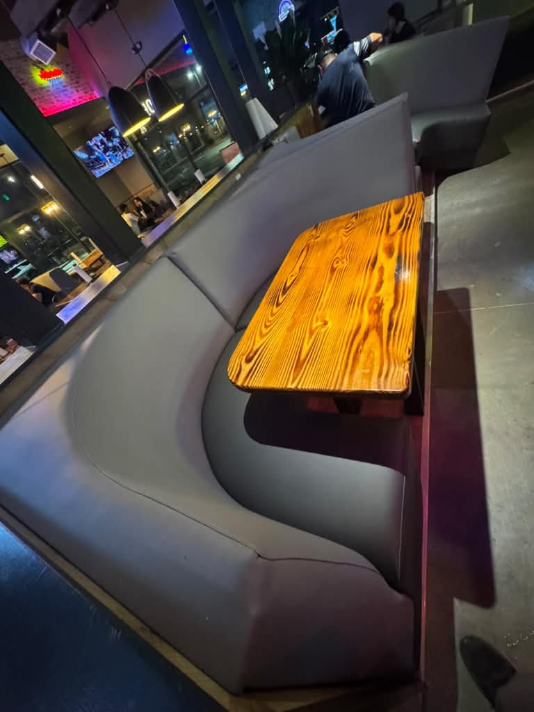 Grey curved booth seating with live-edge wood table in night bar